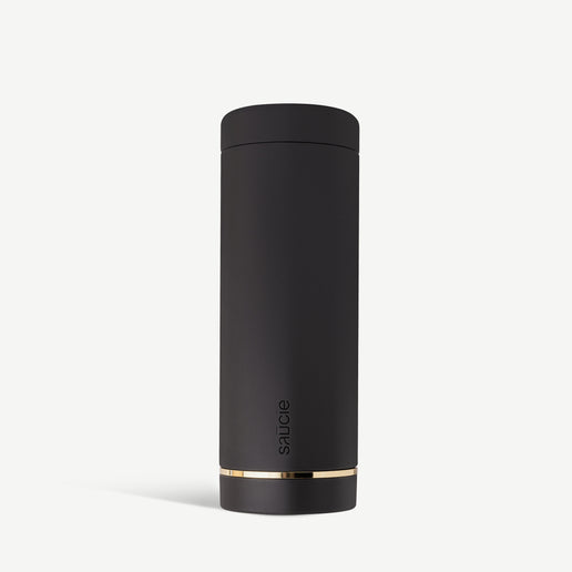 A black reusable sauce bottle with a gold band near the base, standing upright